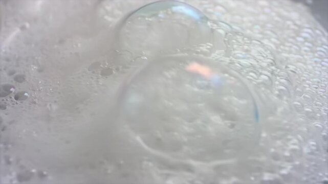Extreme close-up of a growing foam layer as bubbles multiply and merge across the surface, with camera sliding parallel to capture fluid motion, texture evolution and cleansing or chemical reaction