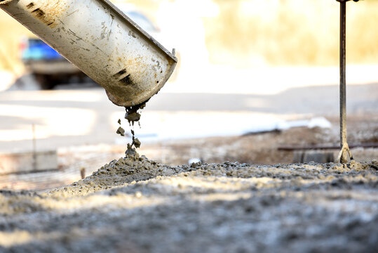 Concrete Pouring Construction: A close-up view captures the precise moment when concrete is being poured onto a construction site, emphasizing the raw texture and structural essence.
