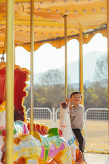 Happy young Asian boy riding a carousel at an amusement park in China © sweetriver