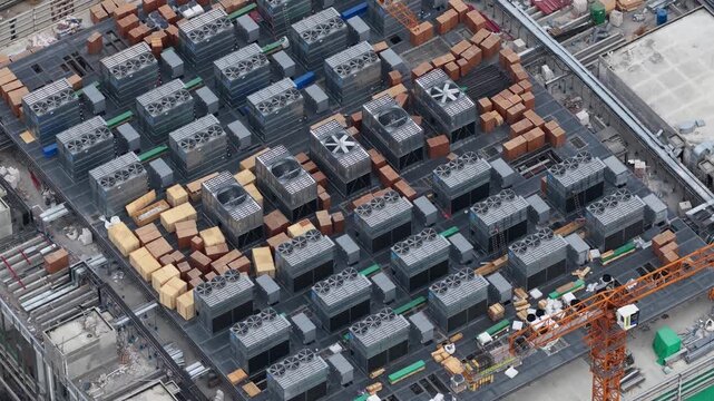 Close aerial drone view of rooftop cooling systems on a hyperscale data center under construction, showing thermal infrastructure, industrial engineering, and digital facility development.