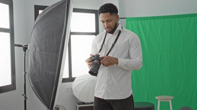 Man with camera adjusts lens and checks settings in studio, gesturing with hand near strap; focused concentration.
