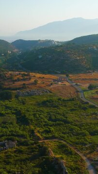 Vertical video. Gelemis, Turkey. Ancient gate, modern roadway and Hurmalik Hamami thermal complex at Tepecik in Patara, historical and contemporary elements. Aerial View. Rich colors