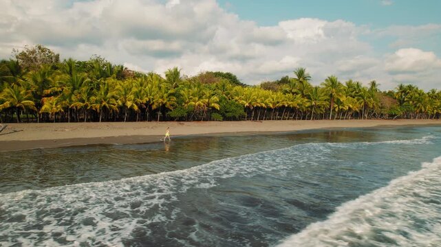 Woman enjoying a jog by palm trees on tropical beach with calm ocean waves