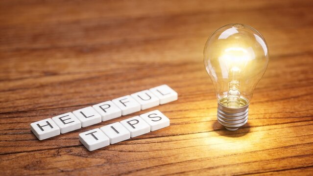 A lightbulb shines beside helpful spelling tiles on wood.
