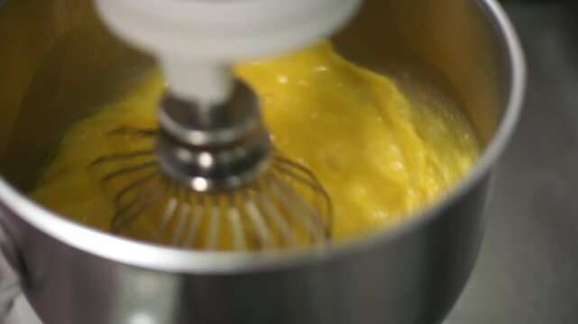 Stand mixer whisking yellow egg yolk mixture for bakery