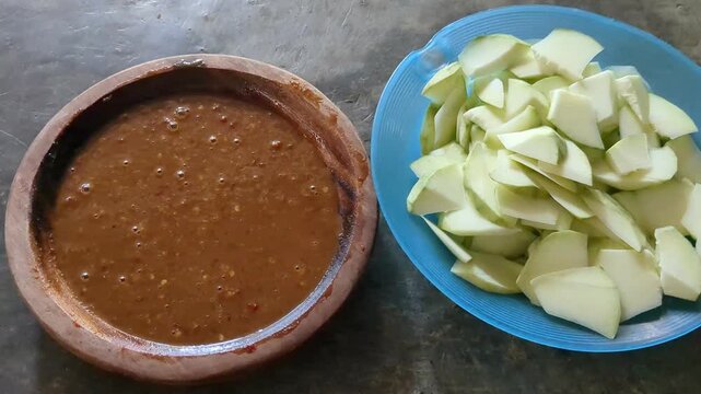 Fresh sliced green mango with spicy dipping sauce in traditional clay bowl