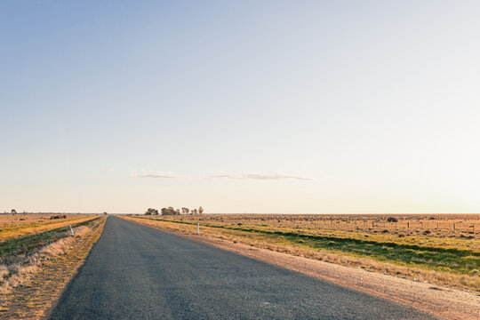 Long, straight road stretching into the horizon under a vast, clear sky