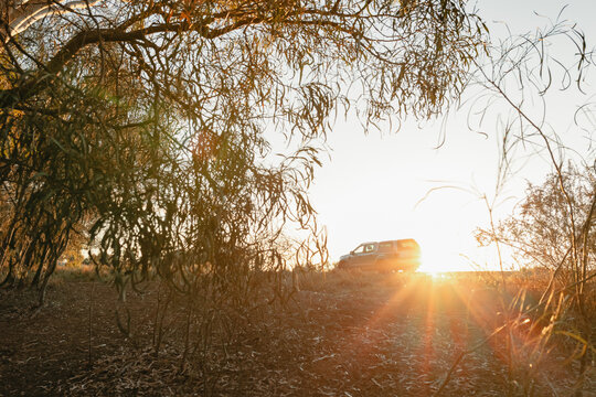Off road vehicle parked along a dusty track during a golden sunset with lens flare