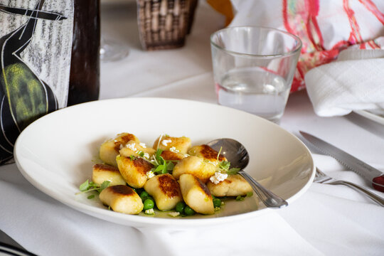 Bowl of Gnocchi with serving spoon on a dinner table