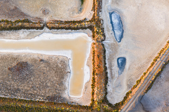Aerial view of levee banks and colourful evaporation ponds at a coastal salt works