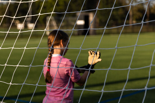 girl playing soccer putting on goalkeeper gloves