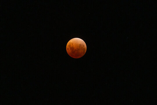 Blood moon eclipse glowing orange in the vast darkness of the night sky