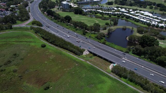 Cars Driving Across The Pacific Motorway Near Firth Park In Robina, QLD, Australia. Aerial Drone Shot