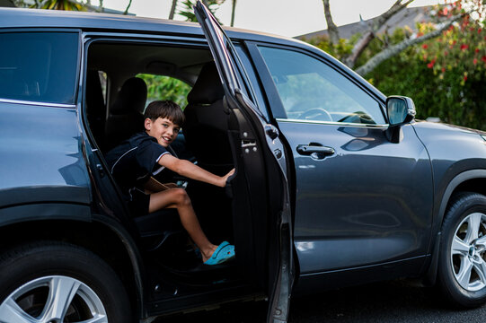 Young boy sitting in the back seat closing the car door