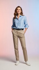 Fototapeta premium A woman stands confidently in a studio setting wearing a light blue button-down shirt with rolled-up sleeves, khaki pants, a black belt, and white shoes