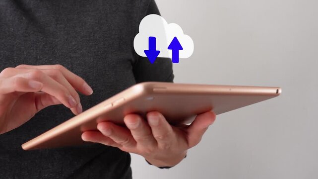 A person is holding a tablet with a cloud icon showing arrows for uploading and downloading data. The cloud symbol suggests data transfer or cloud storage.