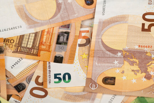 Closeup layered fifty euro banknotes showing security features, hologram and microprint visible, textured paper fibers, highdetail macro, editorial finance concept