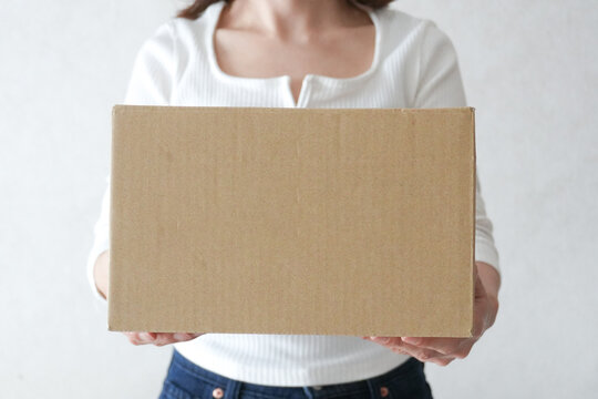 段ボールを持った女性の手元　荷物