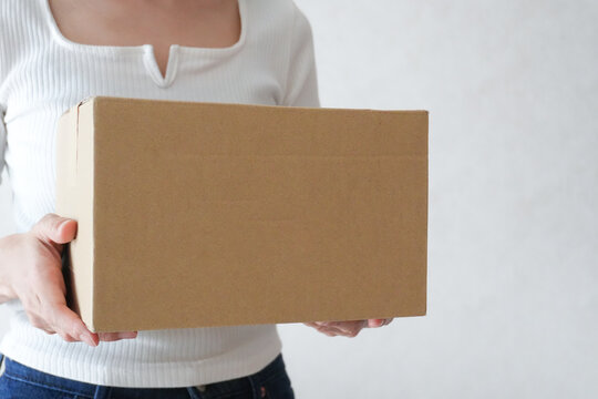 段ボールを持った女性の手元　荷物