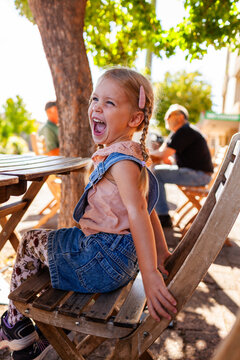 Happy little girl at cafe laughing while waiting for order to arrive
