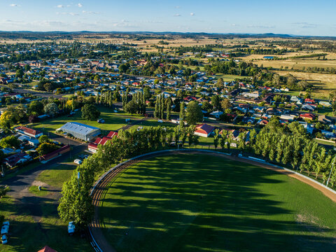 Green trees around Glen Innes Showground ring in bright sunlight from aerial view in summer 
