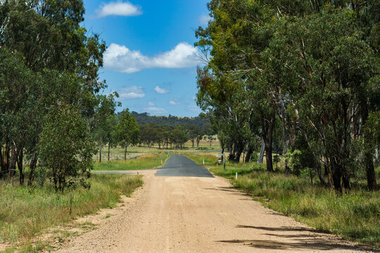remote gravel road changing to sealed road in remote farmland bushland