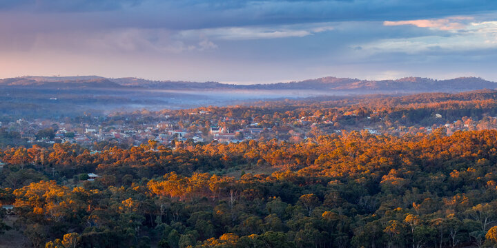 Aerial panorama view of twilight colours and golden light over a rural town nestled in forest valley