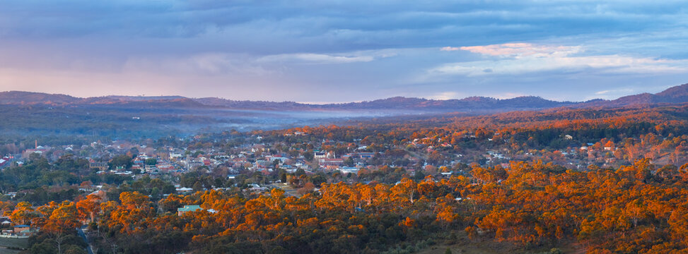 Aerial panorama view of twilight colours and golden light over a rural town nestled in forest valley