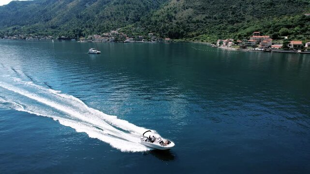 Swift boat zips across turquoise waters peacefully. Vivid scene of boat racing past green mountains and coastline