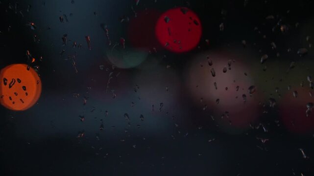 Raindrops on a car window with blurred background of street traffic lights