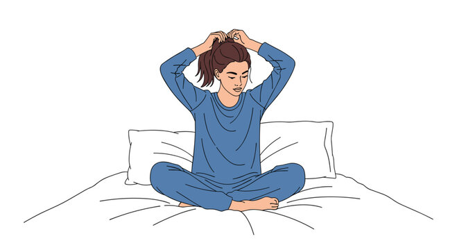 A young woman dressed in comfortable blue pajamas sits peacefully on a soft white bed while gathering her long brown hair into a high ponytail style.