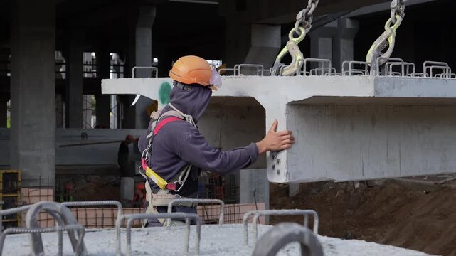 Construction worker guiding precast concrete slab installation
