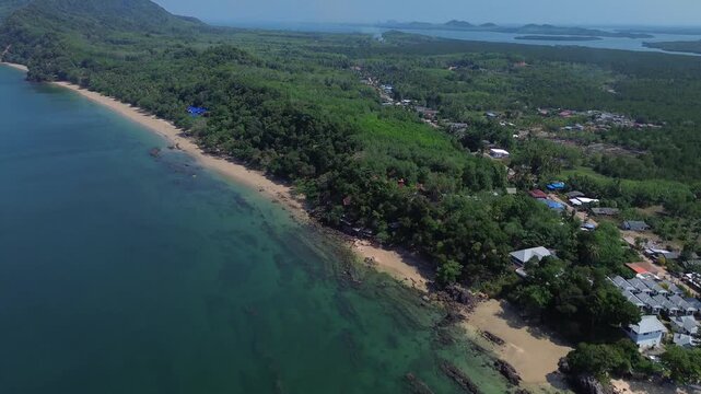 Aerial drone view of tropical coastal village on Koh Jum Thailand with calm sea sandy shoreline lush green jungle and peaceful island landscape authentic Southeast Asia scenery