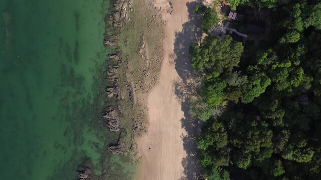 Top down drone shot of coastal textures on Koh Jum Thailand featuring rocky reef formations shallow clear water sandy beach and dense jungle edge abstract natural patterns and remote island scenery