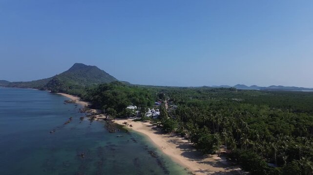 Cinematic drone shot of remote jungle coastline on Koh Jum and Koh Pu in Krabi Thailand featuring rugged shoreline tropical forest and a distinct island mountain ridge and islands in the distance.