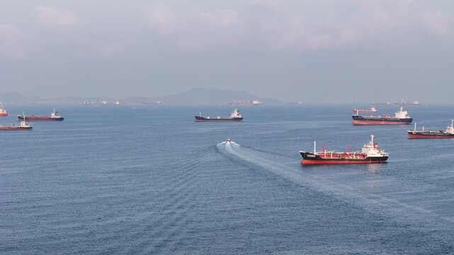 fast patrol boat LPG gas and oil tanker ships anchored in the ocean, with a fast patrol boat in the foreground. Global energy transport, war energy crisis, and Strait of Hormuz blockade
