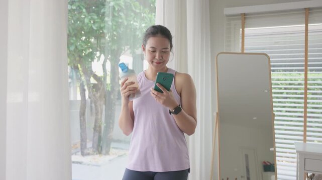 Young gen z active woman drink whey creatine shake bottle eating diet food using phone calorie plan app after home sport workout. health care asia people happy relax protect aging life weight loss.