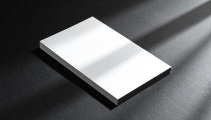 Fototapeta premium A sleek rectangular object sits on a dark surface with light shining on it.