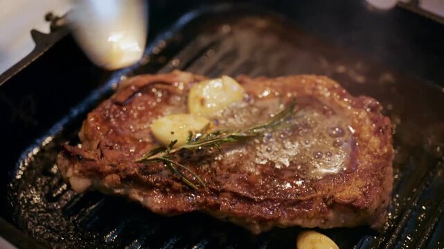 Juicy steak basted with butter and herbs in hot pan slow motion footage.