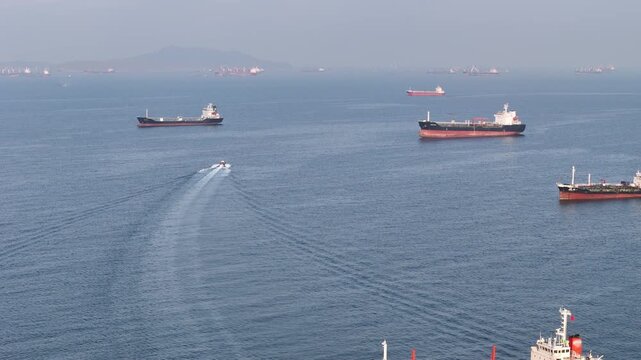 fast patrol boat LPG gas and oil tanker ships anchored in the ocean, with a fast patrol boat in the foreground. Global energy transport, war energy crisis, and Strait of Hormuz blockade