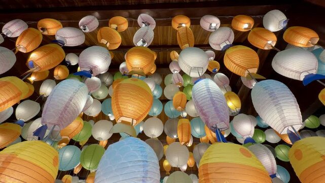 Low angle view of numerous hanging paper lanterns creating a vibrant ceiling display, festive atmosphere, celebration decor, warm ambient lighting
