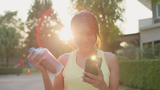Young active woman drink whey protein shake bottle eating diet food using phone calorie AI plan app after workout health care asia people happy relax anti aging life weight loss walk public green park