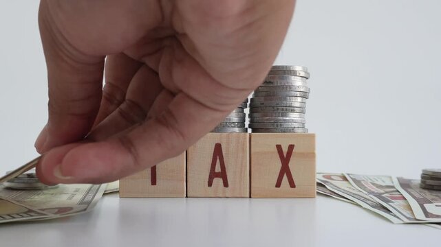 Tax concept using wooden blocks with TAX written on them and coins and dollar bills