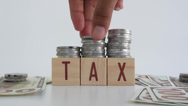 Tax concept using wooden blocks with TAX written on them and coins and dollar bills