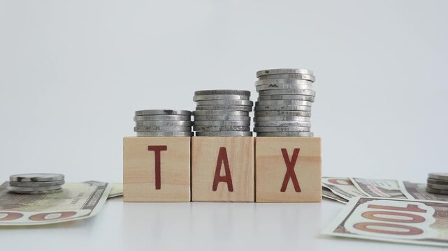 Tax concept using wooden blocks with TAX written on them and coins and dollar bills