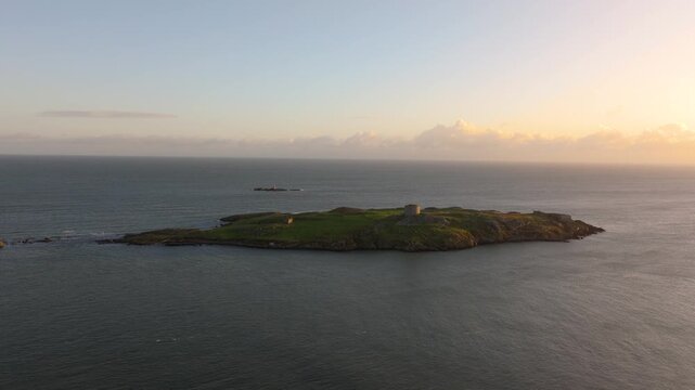 Dalkey Island with its historic Martello Tower stands against a serene sunset backdrop. Ideal for travel, history, and coastal scenery projects.