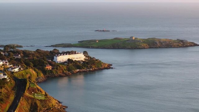 A historic manor overlooks Dalkey Island with its Martello Tower, set against a serene ocean backdrop. Ideal for travel promotions or historical documentaries.