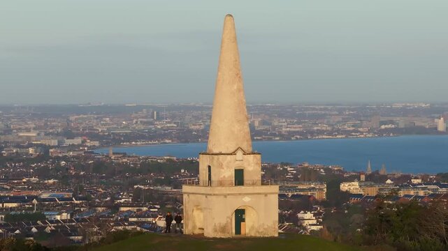 The obelisk stands on Killiney Hill, offering a sweeping view of Dublin's vibrant cityscape and bay. Ideal for urban landscape and travel content.