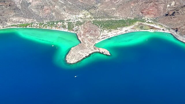 4K drone aerial of Ballena Pel&eacute;chada beach near Muleg&eacute;, featuring a unique whale tail rock formation, bright blue water, and desert coastline.