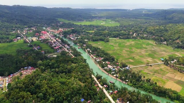 high angle aerial view of Loboc River Flowing Through Green Countryside rice field Landscape In Bohol Philippines, boat offering tour cruise to tourist